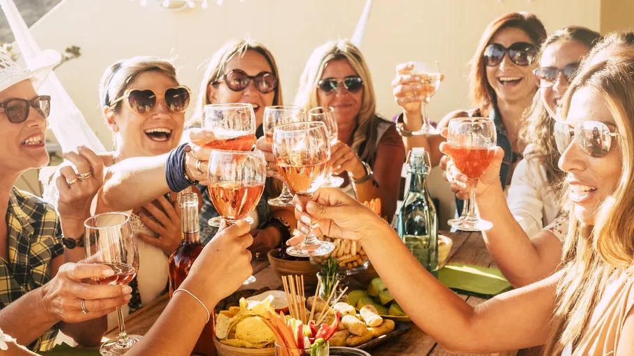 Group of women toasting with drinks outdoors.