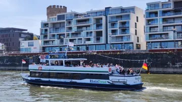 Passenger boat cruising near modern apartments.