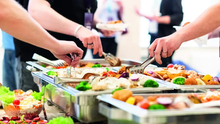 People serving food at a buffet table.