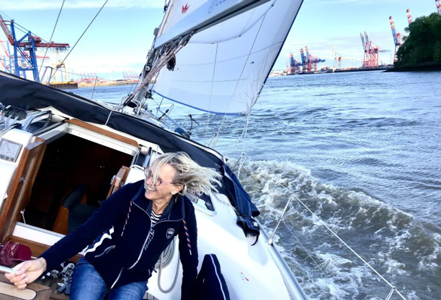 Frau lächelt auf einem Segelboot nahe Hafenkranen.