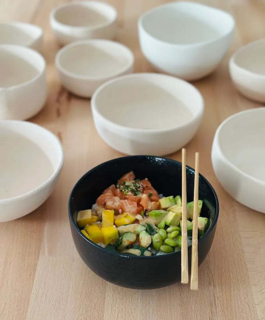 Poke bowl with chopsticks on wooden table.