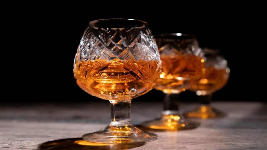 Three crystal glasses filled with amber liquid.