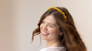 Woman with flower headband smiling and turning.