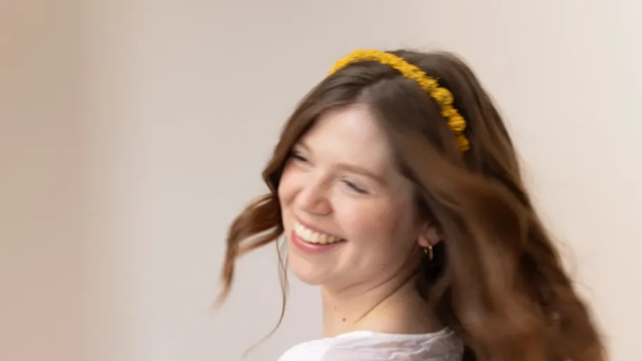 Frau mit Blumenhaarreif lächelt und dreht sich.