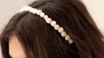 White beaded headband on brown hair.