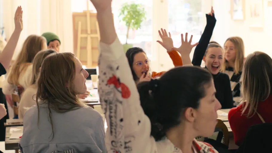 People raising hands in a classroom.