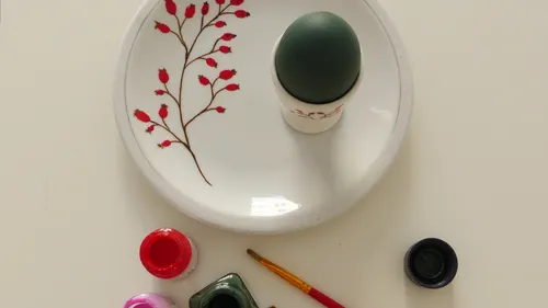 Bemaltes Ei auf Teller mit Pinseln und Farben.