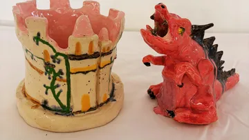 Ceramic dragon and castle on white surface.