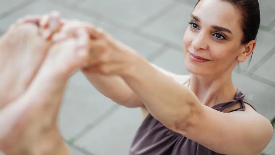 Woman performing yoga pose outdoors smiling.