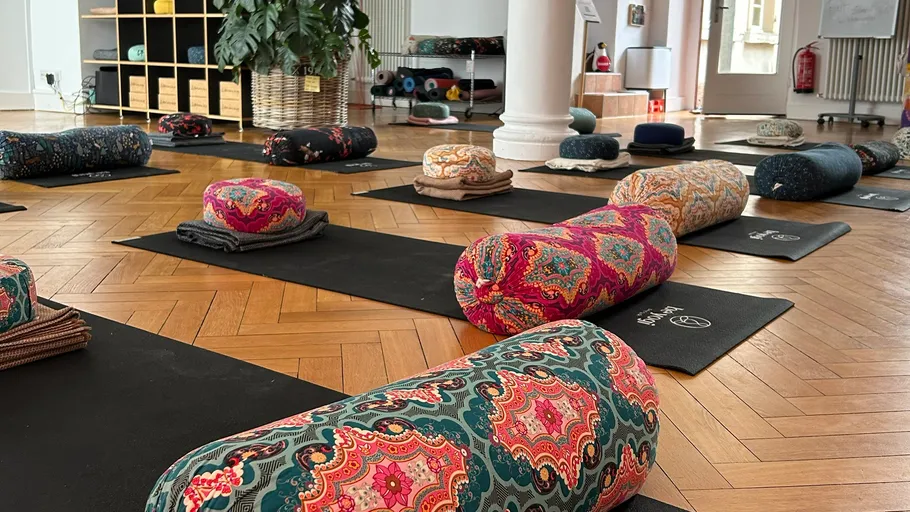 Yoga mats with colorful bolsters in room.