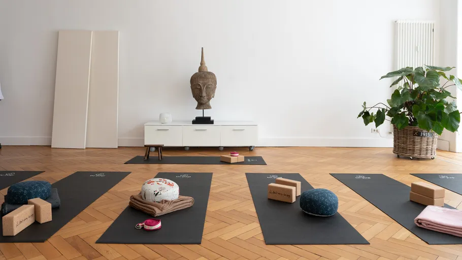 Yogamatten mit Kissen, Blöcken und Buddha-Statue.