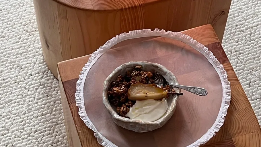 Schale mit Joghurt und Birne auf Holztisch.