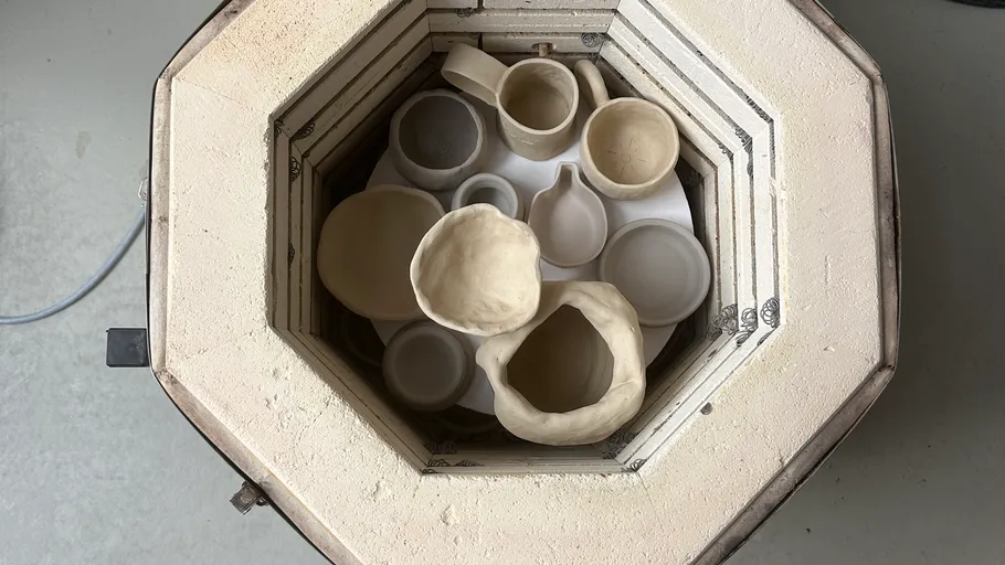 Pottery inside kiln, top view, various shapes.