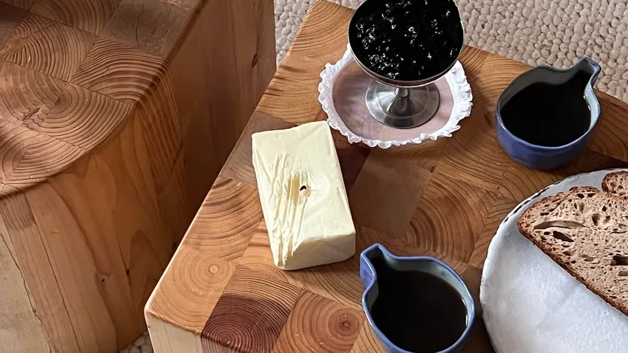Butter, jam, and coffee on wooden table.