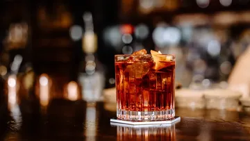Roter Cocktail mit Eis auf Holztheke.