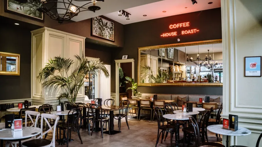 Cozy café with tables, chairs, and neon sign.