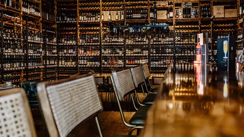 Bar counter facing extensive wine bottle shelves.