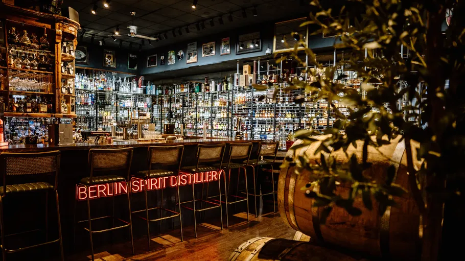 Bar interior with neon sign and bottles.