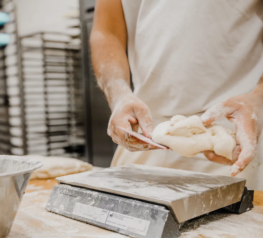 Baker weighing dough on a scale.