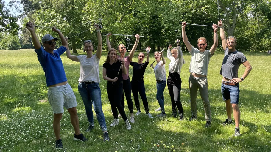 People raising arms with sticks in a park.