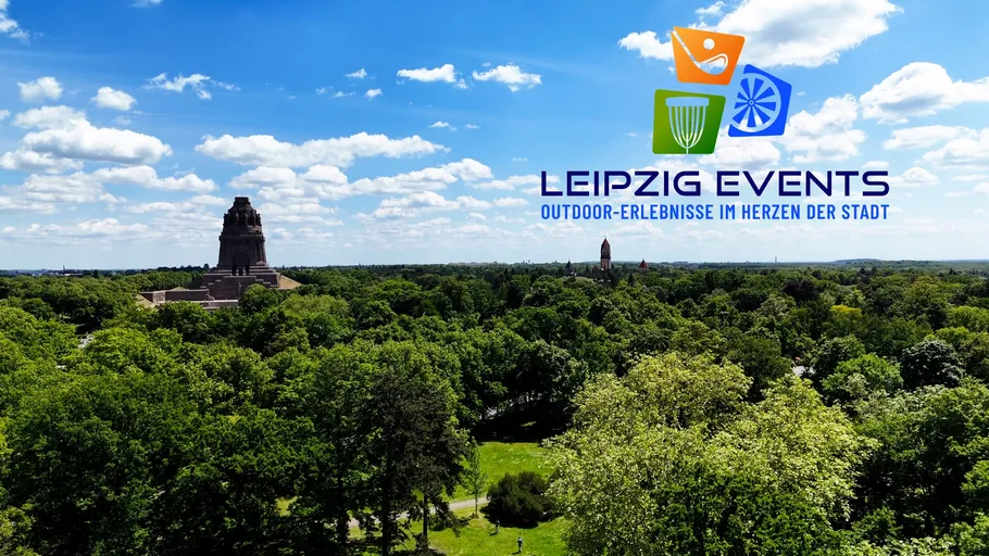 Monument in park with event logo, blue sky.