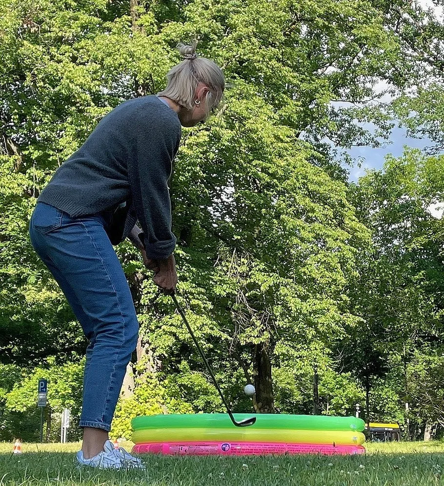 Person playing golf with kiddie pool target.