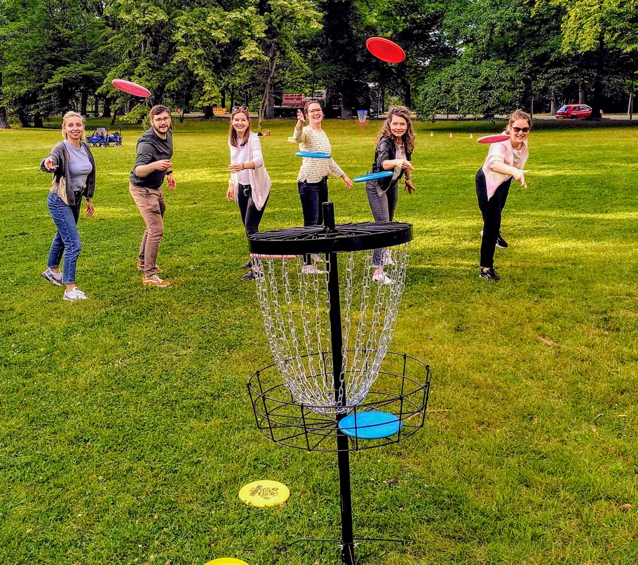 Gruppe spielt Discgolf im grünen Park.
