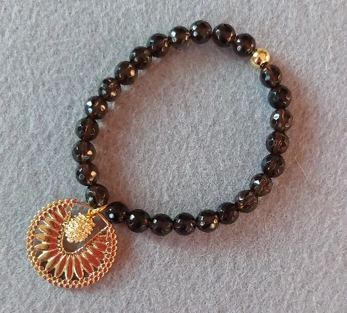 Beaded bracelet with gold pendant on felt.