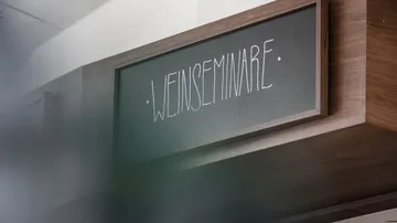 Wooden sign reads 'WEINSEMINARE' in white text.
