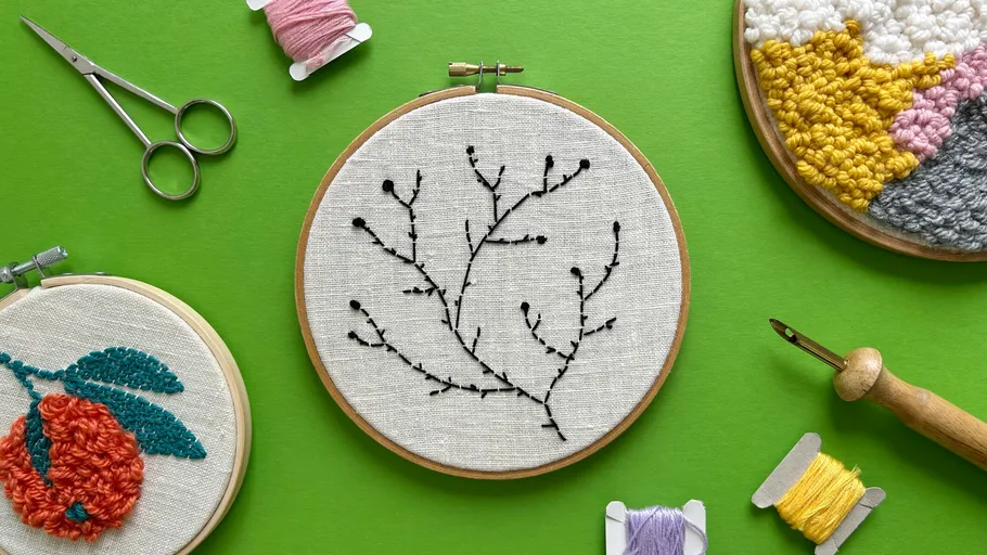 Embroidery hoops with designs on green background.