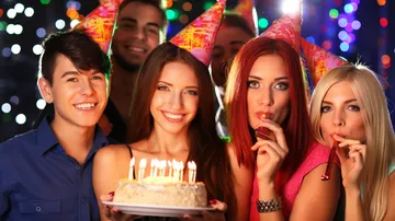 Gruppe mit Partyhüten und Geburtstagstorte.