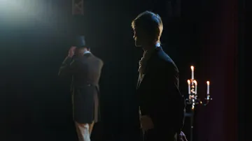 Two actors on stage in dim lighting.