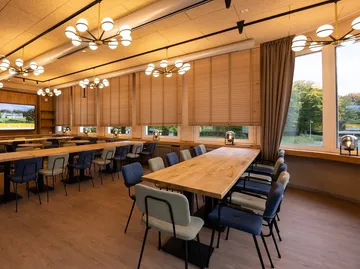 Moderner Speisesaal mit Holztischen und Stühlen.