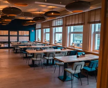 Empty restaurant with wooden tables and large windows.