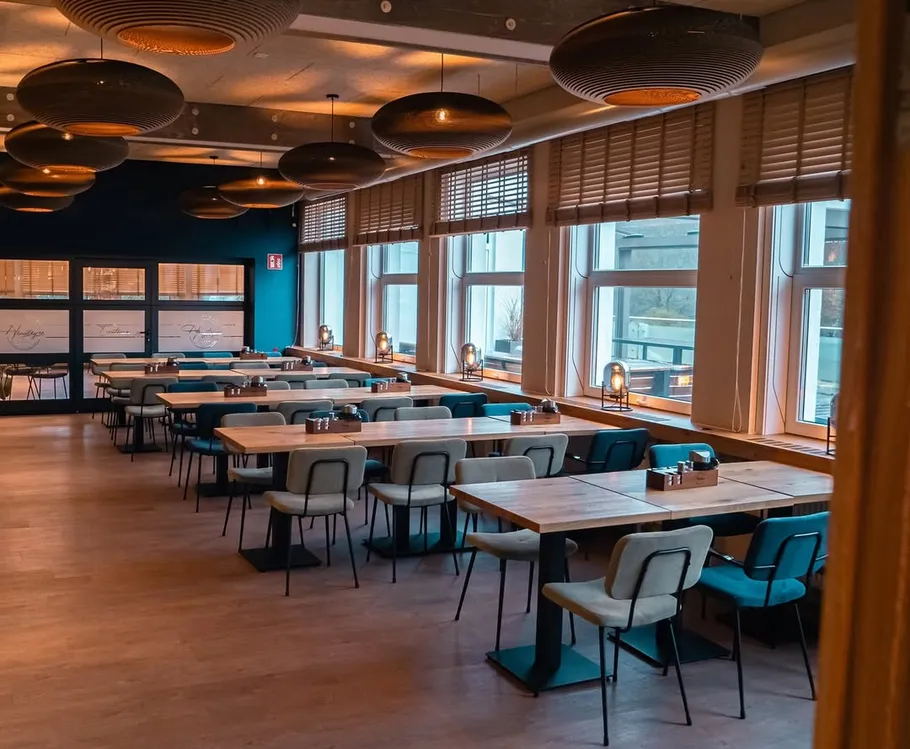 Empty restaurant with wooden tables and large windows.