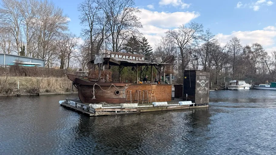 Floating barge with wooden bar on river.