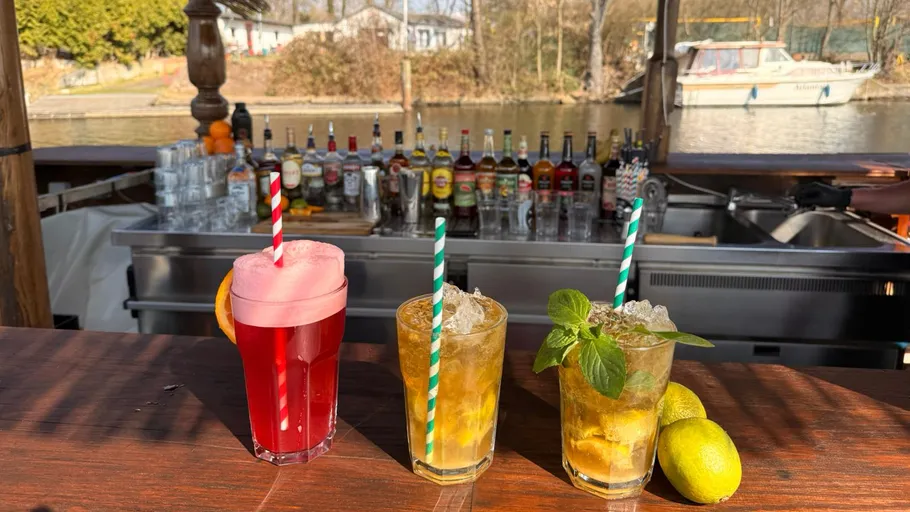 Three cocktails on a bar near a river.