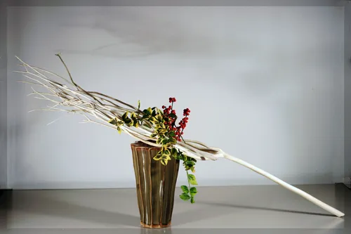 Ikebana-Gesteck in hohem Keramikvase.