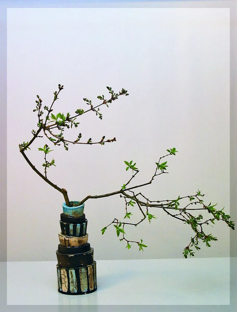 Künstlerische Vase hält knospigen Zweig, minimalistischer Hintergrund.