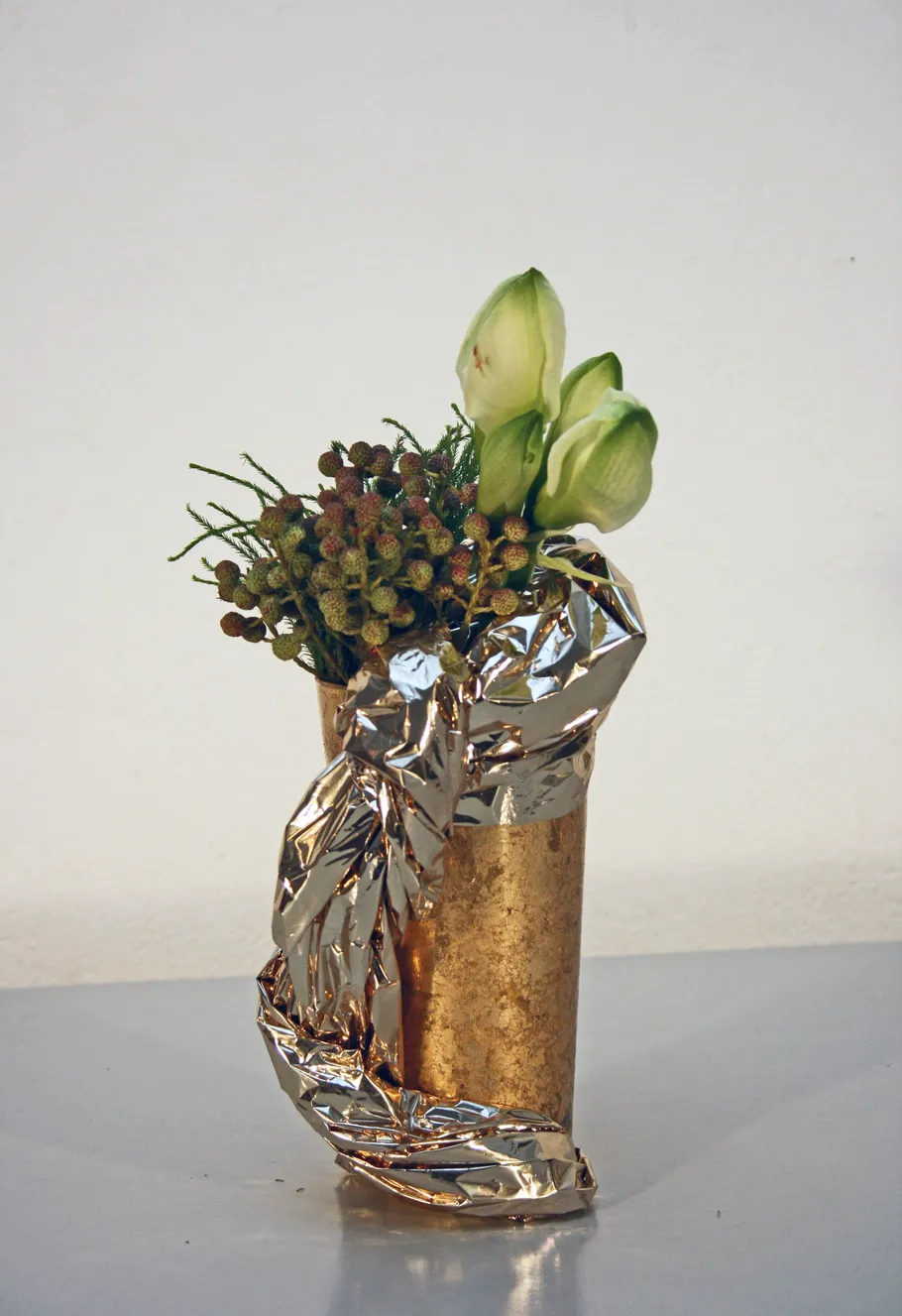 Goldene Vase mit Blumen auf Tisch.