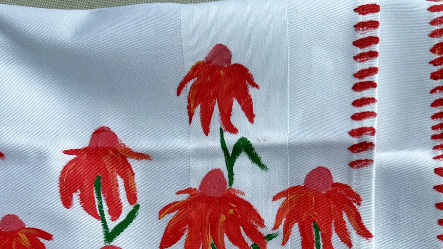 Red flowers painted on white fabric.