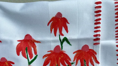Red flowers painted on white fabric.