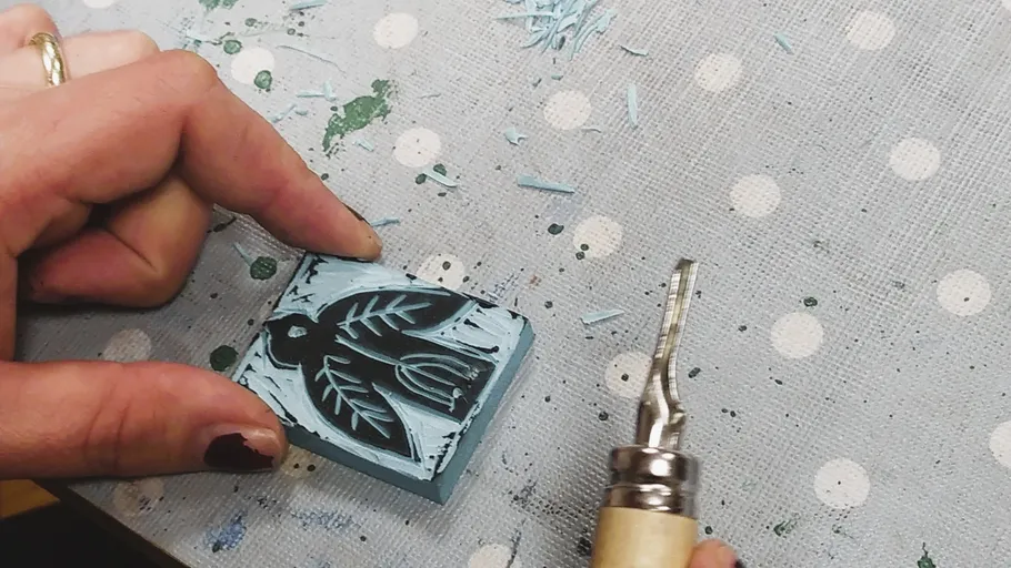 Hand schnitzt Vogeldesign auf Linoleumblock.