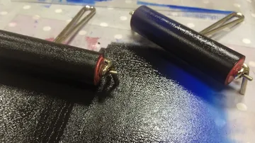 Zwei Farbwalzen verteilen schwarze Tinte auf Oberfläche.