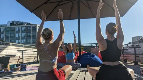 Drei Frauen beim Yoga auf Dachterrasse.