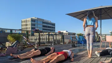 Three women practicing yoga on a rooftop.