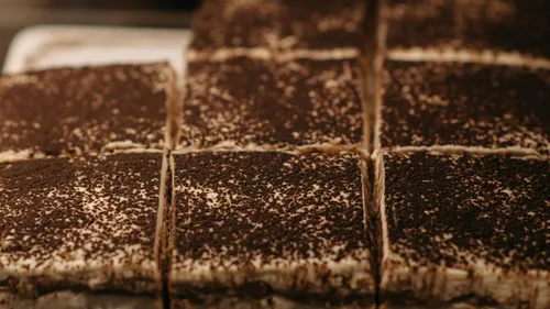Sliced tiramisu topped with cocoa powder.