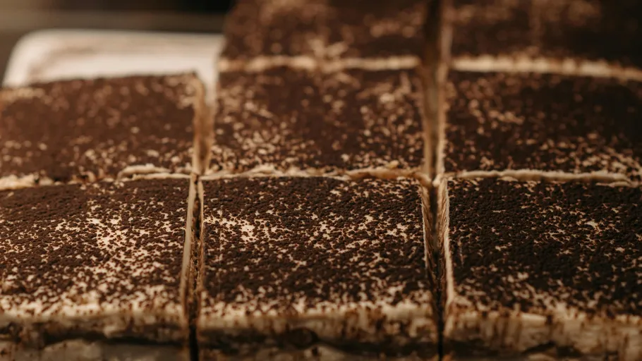 Geschnittenes Tiramisu mit Kakaopulver bestreut.