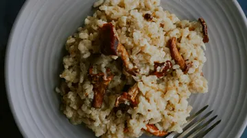 Mushroom risotto on a white plate with a fork.