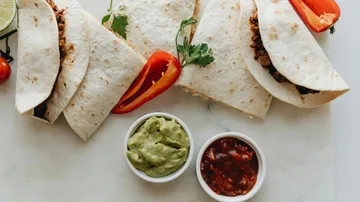 Tacos mit Guacamole und Salsa auf Marmor.
